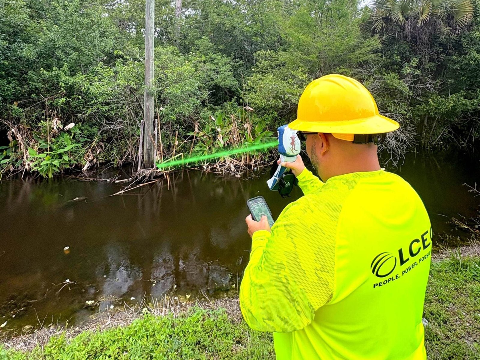Electric cooperative lineman using a Skadi GNSS receiver with laser offset to map a pole across a canal