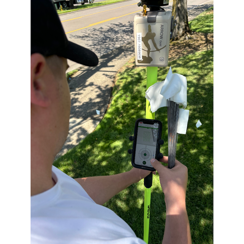 field worker holding white flags, a range pole, an Eos Arrow Gold GNSS Receiver and Fast XY open on a phone.